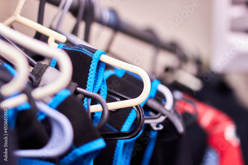 Closeup macro of wetsuits hung up on coat hangers in a wet room cloak room with shallow depth of field photo