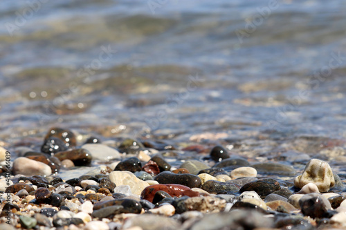 Pebble stones on blurred background of sea waves. Summer beach, vacation concept