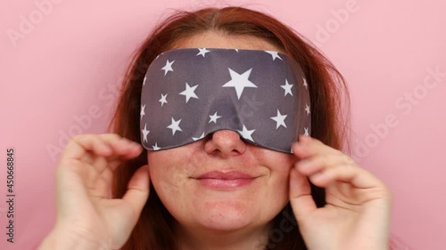 Portrait of happy caucasian girl with sleeping mask stretching after sleep in morning isolated over pink background. photo