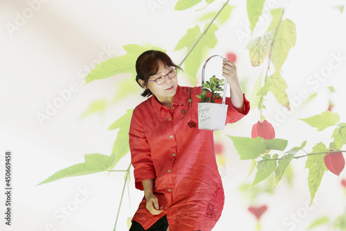 붉은색 옷을 입은 한국의 평범한  50대 주부가 작은 꽃이 핀 꽃 바구니를 들고 있는 모습입니다. 