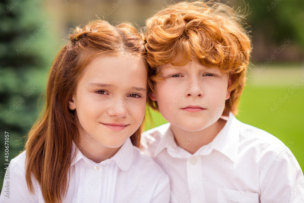 Photo of ginger redhead sister brother schoolchildren look camera wear white shirt uniform park outside Photo of ginger redhead sister brother schoolchildren look camera wear white shirt uniform park outside