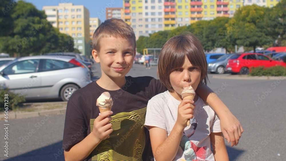 Boys eat ice cream in the city. Good brothers spend the weekend together during the holidays. Sweets delight children, the positive effect of glucose on the developing human body.