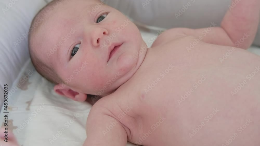 Newborn baby boy hiccups lying in bed, crib and child looks up suffering from hiccupping Newborn baby boy hiccups lying in bed, crib and child looks up suffering from hiccupping