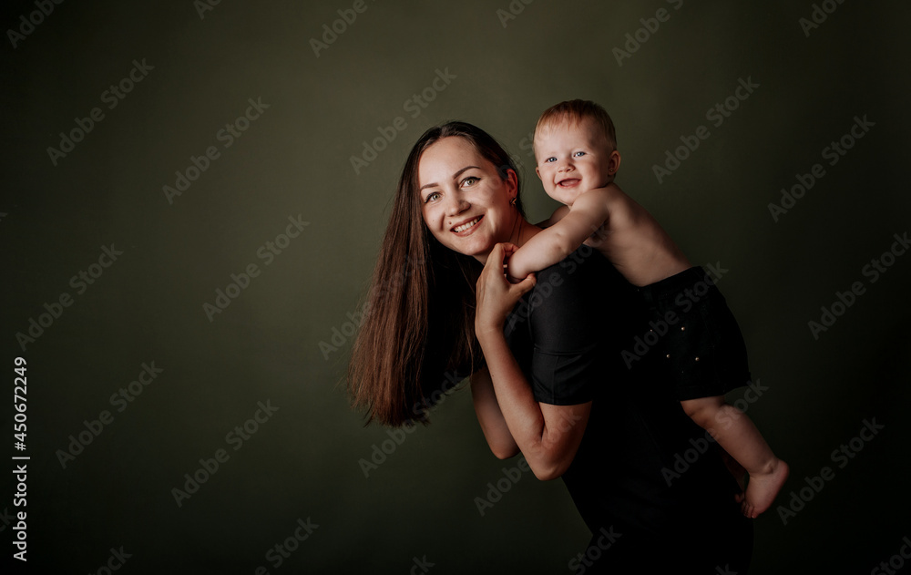 happy brunette mom is playing with her baby daughter on a green background with a place for text happy brunette mom is playing with her baby daughter on a green background with a place for text