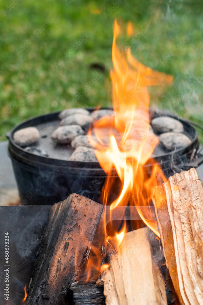 Dutch oven camp cooking with coal briquettes beads on top. Campfire