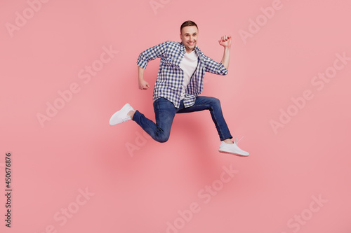 Full size profile side photo of young guy happy positive smile jump go run hurry isolated on pink color background