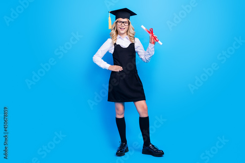 Full length photo of happy charming girl hold hand diploma wear hat tassel isolated on pastel blue color background