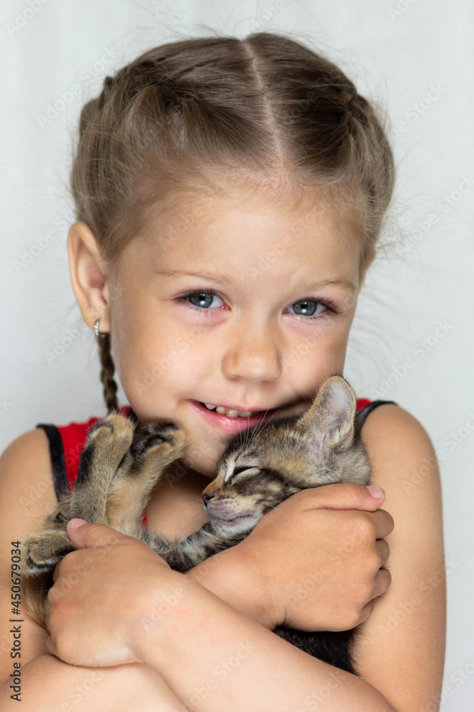 Portrait of cute caucasian girl of five years old holding kitten looking at camera on the white background