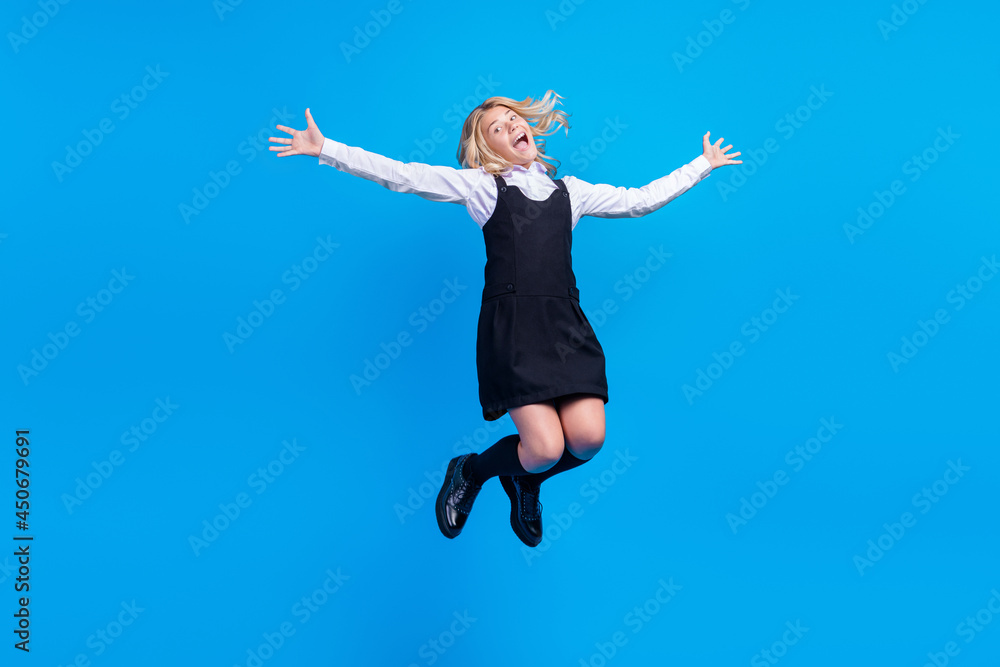 Full body photo of charming happy positive girl crazy jump up enjoy weekend pupil isolated on blue color background Full body photo of charming happy positive girl crazy jump up enjoy weekend pupil isolated on blue color background