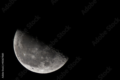 Half a moon in the black night sky. Craters and lunar seas
