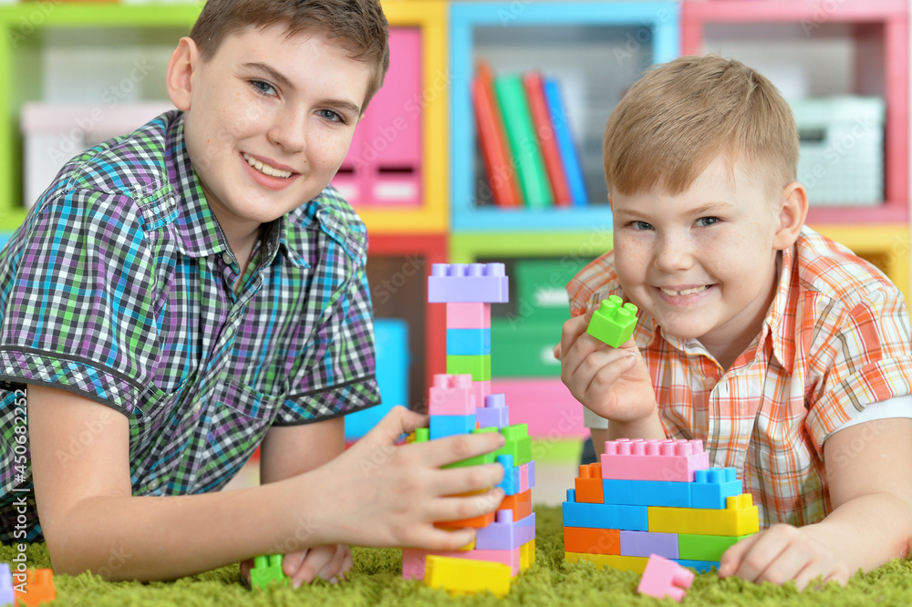 Fototapeta premium brothers playing with colorful plastic blocks in room