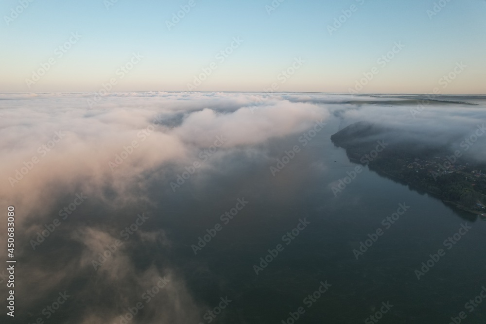 Aerial view of large river with fog above the water. Colorful landscape with forest in low clouds, river, meadow in fog, orange sky with sun in the morning. .Top view. Nature Aerial view of large river with fog above the water. Colorful landscape with forest in low clouds, river, meadow in fog, orange sky with sun in the morning. .Top view. Nature