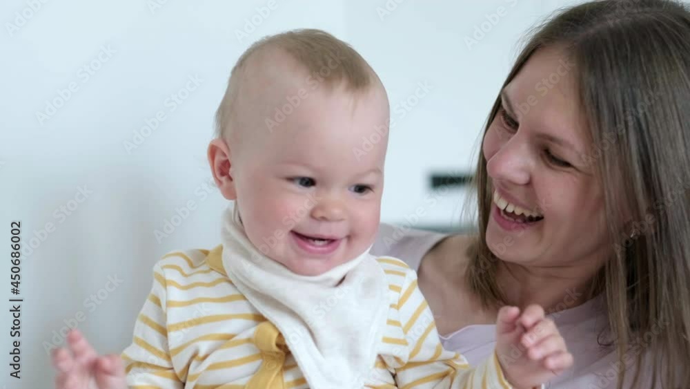 Little infant child laughing having fun and looking in camera. Happy Cheerful Family. Mother And Baby Kissing Little infant child laughing having fun and looking in camera. Happy Cheerful Family. Mother And Baby Kissing