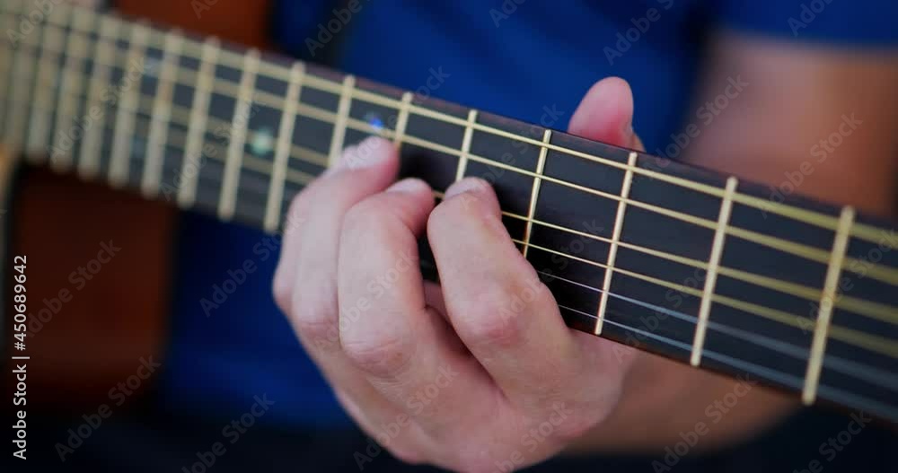 Fingers of Caucasian white man wearing blue shirt playing an acoustic guitar close up at top of fret board. In Cinema 4K (17x9) in 30fps slowed from 60fps. Fingers of Caucasian white man wearing blue shirt playing an acoustic guitar close up at top of fret board. In Cinema 4K (17x9) in 30fps slowed from 60fps.
