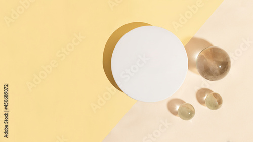 Top view of the blank white cosmetics box on the dual pastel background.Glass sphers near it,concept of the cleanness and clarity.Cosmetic mockup with copy space,large banner. photo