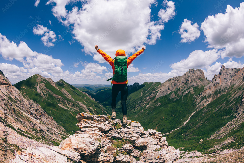 Successful woman backpacker hiking on alpine mountain peak Successful woman backpacker hiking on alpine mountain peak