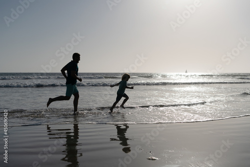 father and son running on beach. daddy with kid boy in sea or ocean. weekend family day.