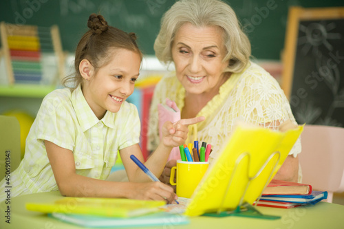 Grandmother with cute little girl doing homework