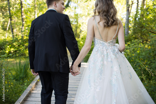 Rear view of well-dressed couple holding hands outdoors.