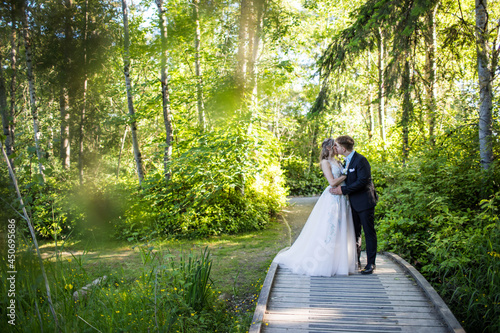 Young romantic couple kiss in forest setting.