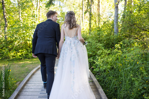 Rear view of young couple walking through lush forest.