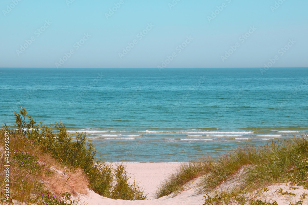 View of the sandy shore against the background of the sea or the ocean with blue sky.
