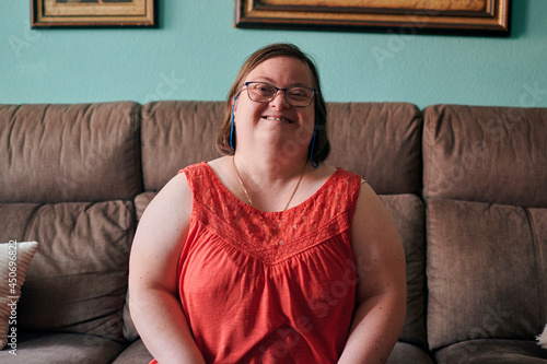 Adult woman with down syndrome smiles and looks at camera at home