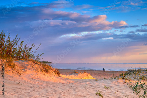 Fototapeta Naklejka Na Ścianę i Meble -  Sand dune illuminated by the setting sun and the shore of the Baltic Sea.