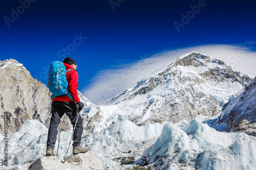 Male backpacker enjoying the view on mountain walk in Himalayas. Face to face with mount Everest, Earth's highest mountain. Travel, adventure, sport concept