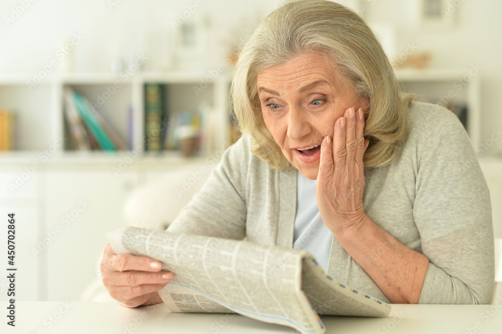 Close up portrait of senior woman reading newspaper Close up portrait of senior woman reading newspaper