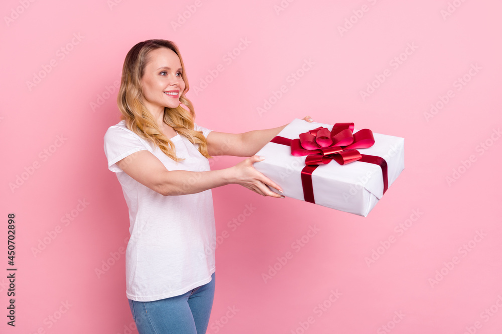 Photo of positive pretty young woman hold hands present box give empty space isolated on pink color background Photo of positive pretty young woman hold hands present box give empty space isolated on pink color background