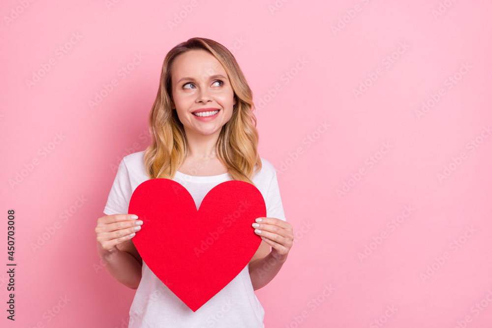 Photo portrait woman in white t-shirt keeping heart looking copyspace isolated pastel pink color background Photo portrait woman in white t-shirt keeping heart looking copyspace isolated pastel pink color background