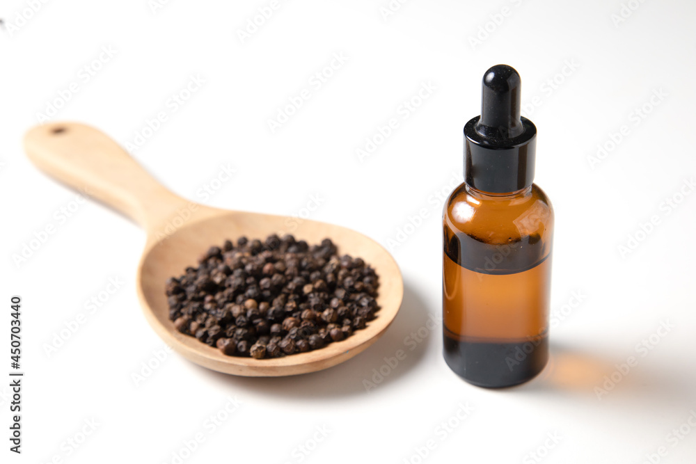 Black Pepper in wooden spoon and bottle of extract on white background. Black Pepper in wooden spoon and bottle of extract on white background.