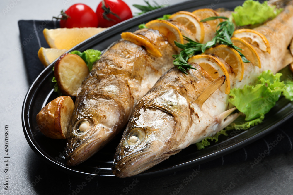 Tasty homemade roasted pike perches with garnish on grey table, closeup. River fish Tasty homemade roasted pike perches with garnish on grey table, closeup. River fish