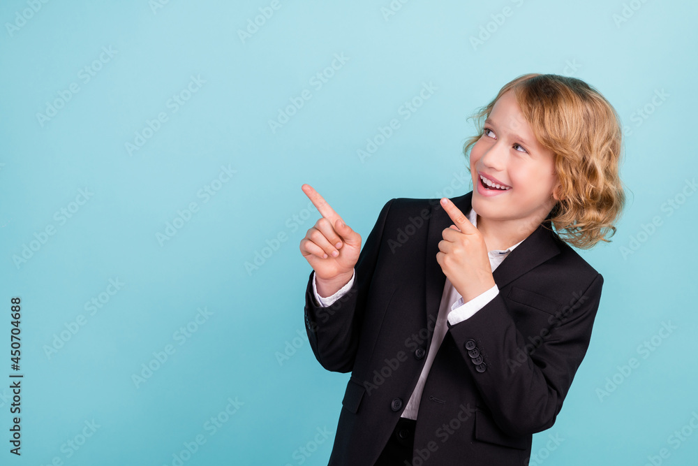 Photo of funny small blond boy point empty space wear uniform isolated on blue color background Photo of funny small blond boy point empty space wear uniform isolated on blue color background