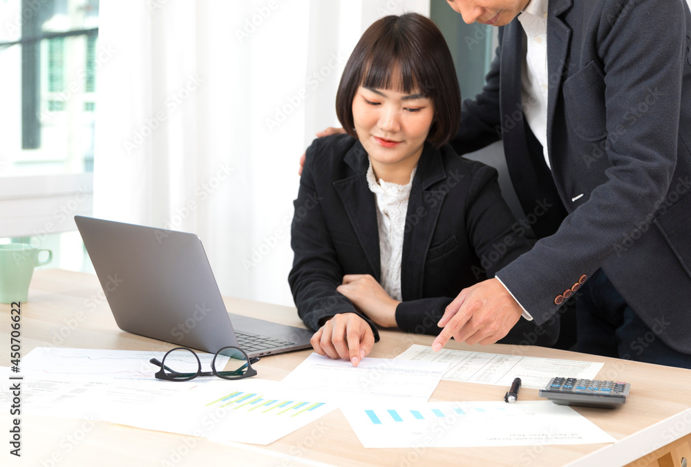 Businesswoman and businessman working together with laptop and graphic charts while sitting at meeting table in modern office. Businesswoman and businessman working together with laptop and graphic charts while sitting at meeting table in modern office.