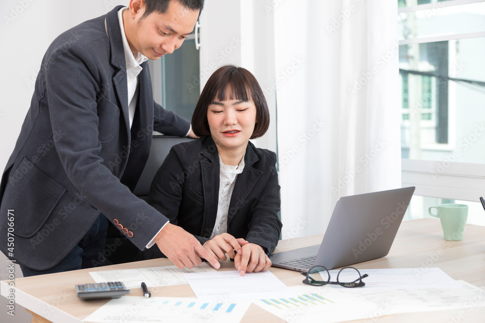 Businesswoman and businessman working together with laptop and graphic charts while sitting at meeting table in modern office. Businesswoman and businessman working together with laptop and graphic charts while sitting at meeting table in modern office.