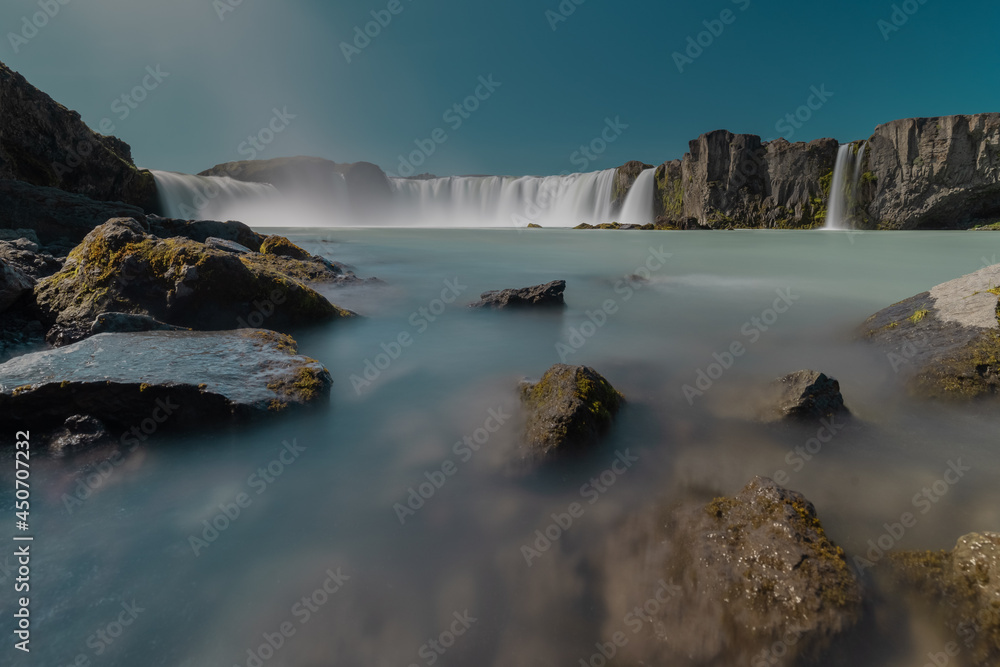 Obraz premium Long exposure photo of magnificent Godafoss waterfall in northern Iceland on a warm summer day. Visible flow of water coming from the waterfall.