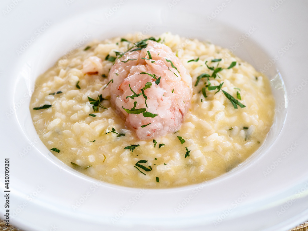 cooked risotto with shrimp tartare in white plate