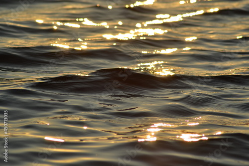 Golden sunlight on calm waves on the sea surface at sunset 