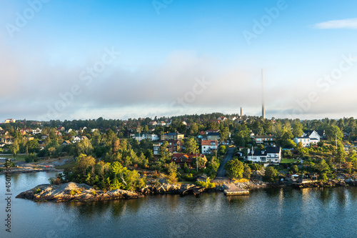 Beautiful view of Stockholm archipelago of the Baltic sea in summer day. Panorama of the shores of Scandinavia Sweden from cruise ship. Forest green islands and coast with villas and buildings.