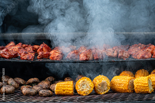 closeup of grill full of delicious food, corn and meat roasts on a garden grill