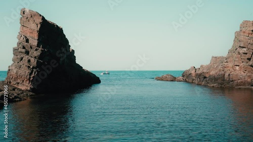 Natural landmark The stone ships in the Black sea, Bulgaria. Colorful landscape of rocks in calm blue sea water during a sunny day. Fishing boat passing between the rocks