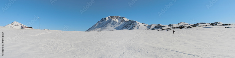 Panorama of Greenland ice, mountains in background, blue sky above