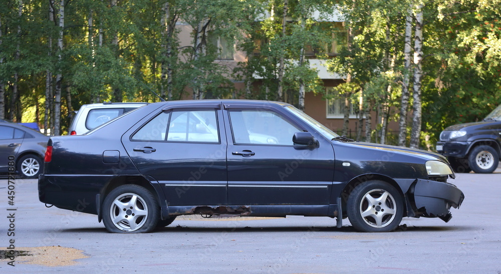 An old rusty broken black car is parked in the courtyard of a residential building, Tovarishchesky Prospekt, St. Petersburg, Russia, August 2021