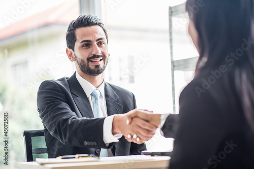 Business man shake hands with business women agreeing on partnerships or introducing themselves for first time meet