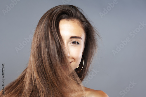 Beautiful brunette girl with hair in the air, studio portrait. Happy smiling face expression.