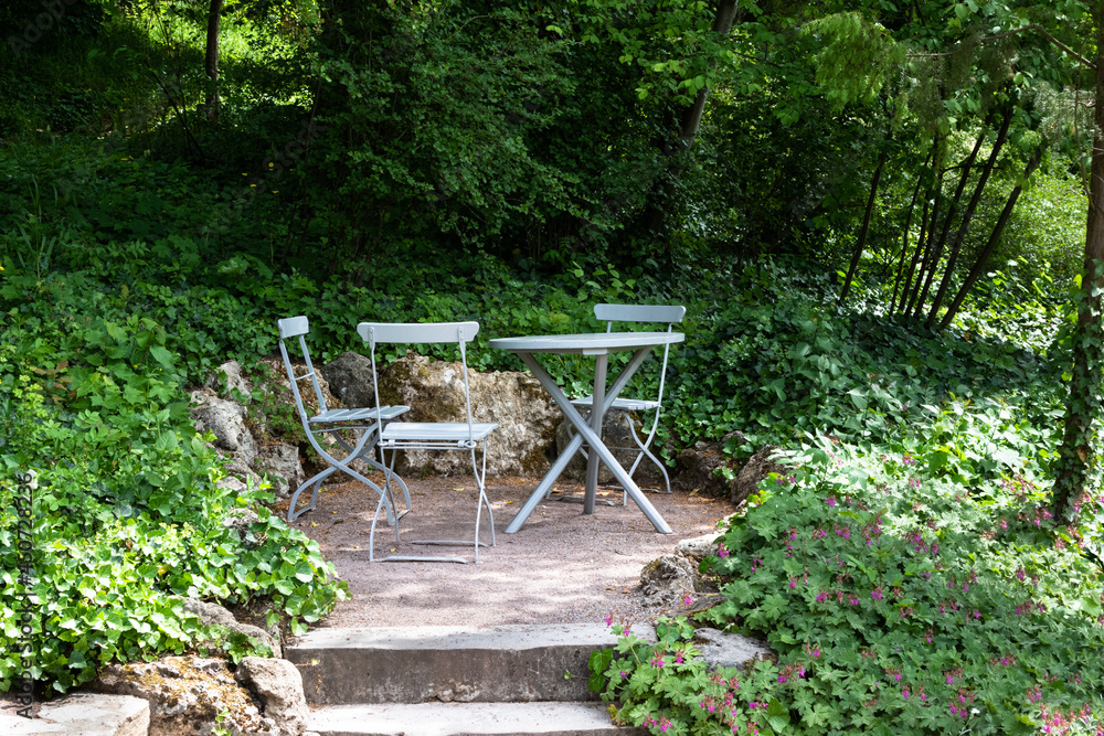 Eine gemütliche Sitzecke im Garten mit Klappstühlen und einem Tisch im Schatten von Bäumen. Eine gemütliche Sitzecke im Garten mit Klappstühlen und einem Tisch im Schatten von Bäumen.