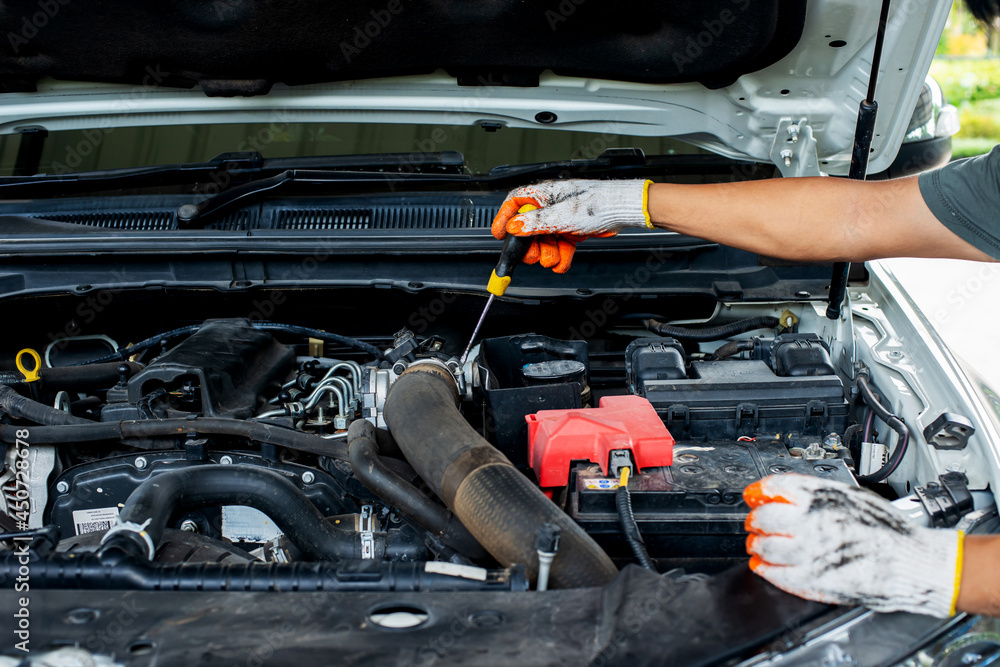 Mechanic using screwdriver to inspect car Mechanic using screwdriver to inspect car