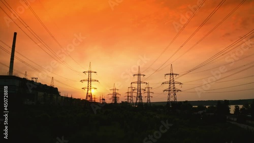 Electricity pylons at sunset. Transmission towers. Silhouette of high-voltage electic towers that transport electric power from generating stations to electrical substations. Aerial view.
